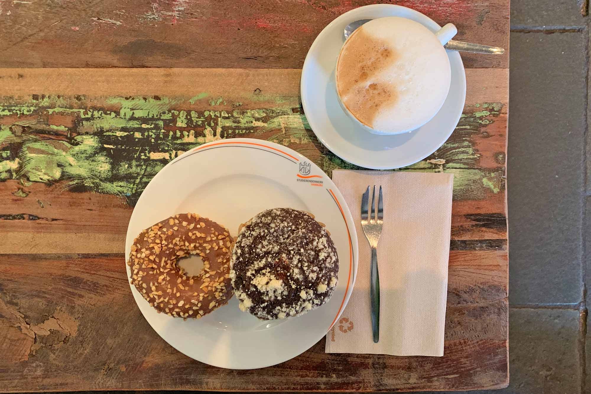 Cappuccino sowie Teller mit Bagel und Schoko-Muffin im Café CampusBlick