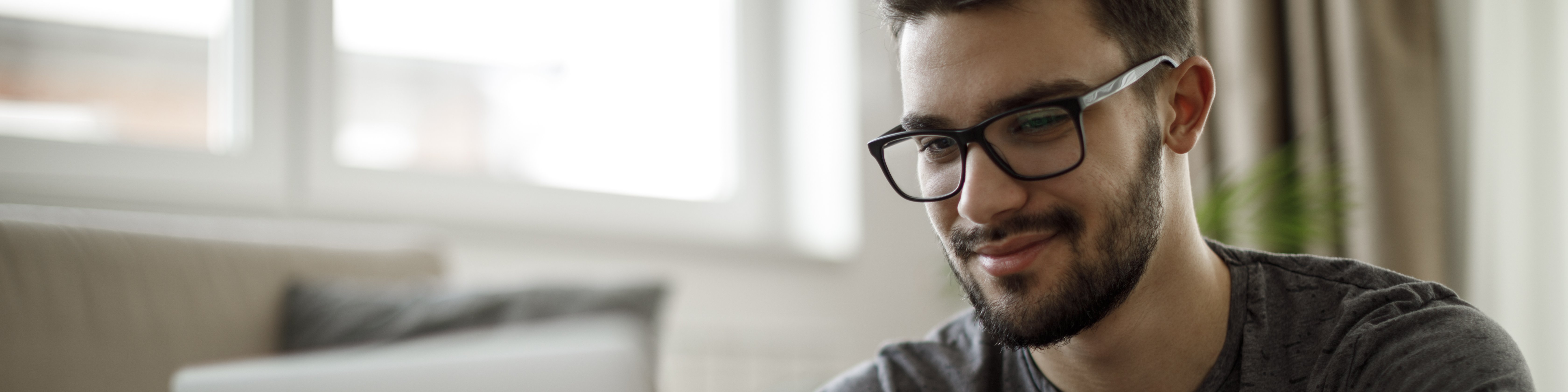 Junger Mann sitzt mit Kaffee vor einem Laptop