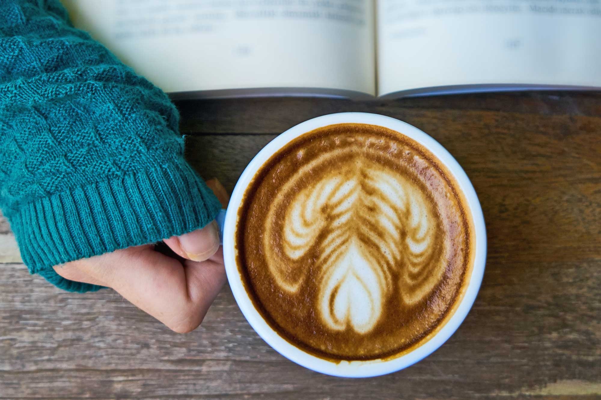 Frau hält eine Tasse Cappuccino in der Hand