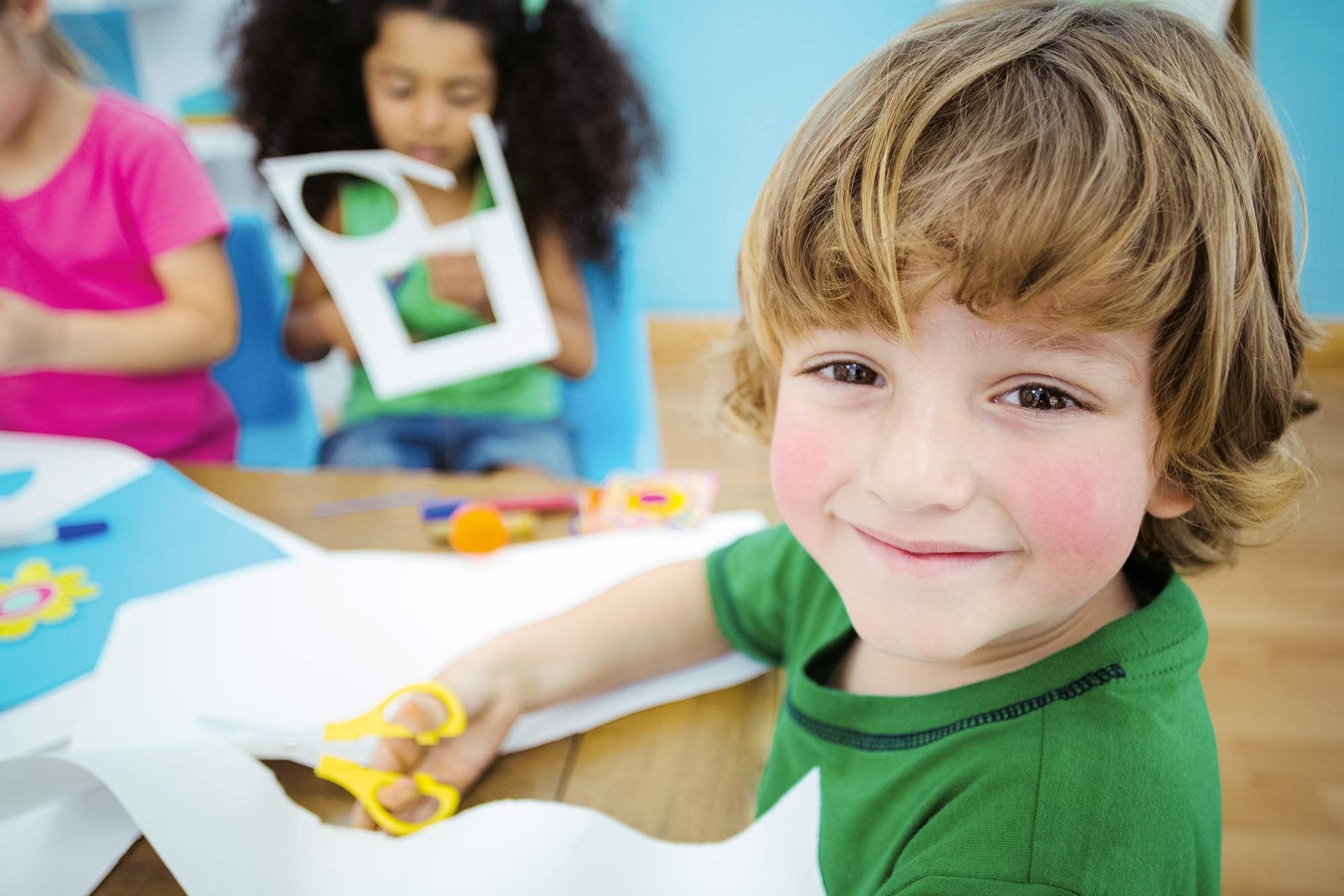 Drei Kleinkinder schneiden Papier mit einer Schere