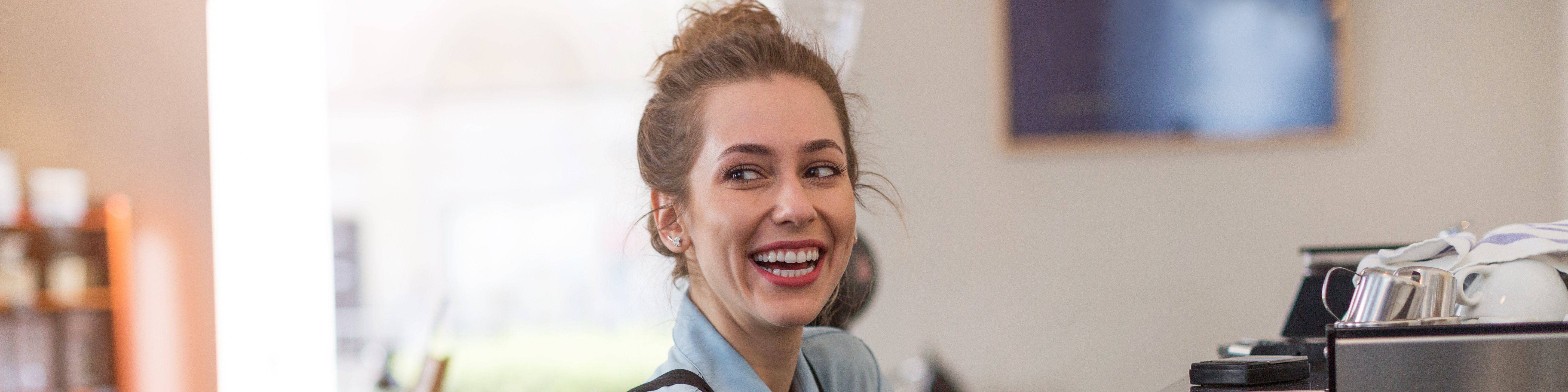 Junge Frau bei der Kaffeezubereitung in einem Café