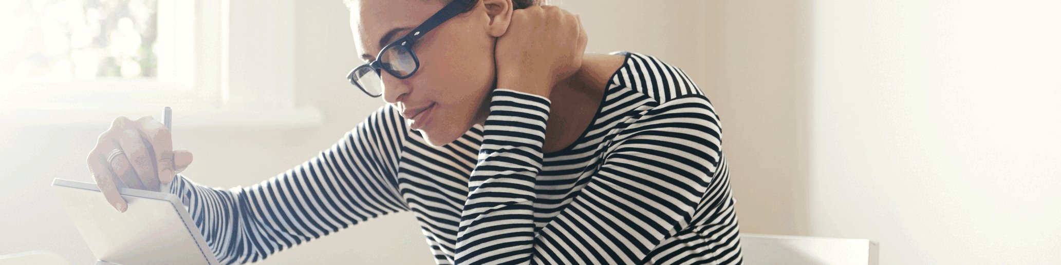 Frau sitzt an einem Tisch vor einem Tablet