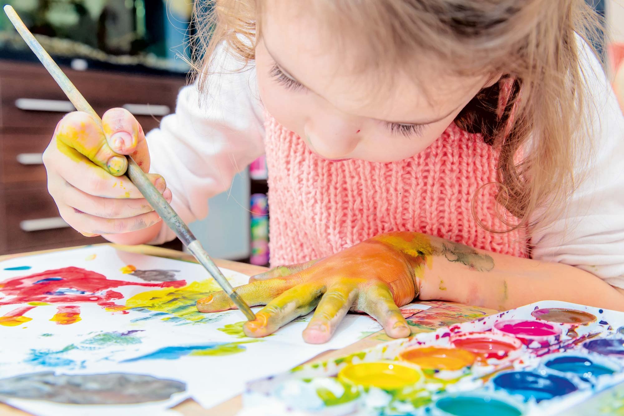 Ein kleines Mädchen bemalt ihre Hände