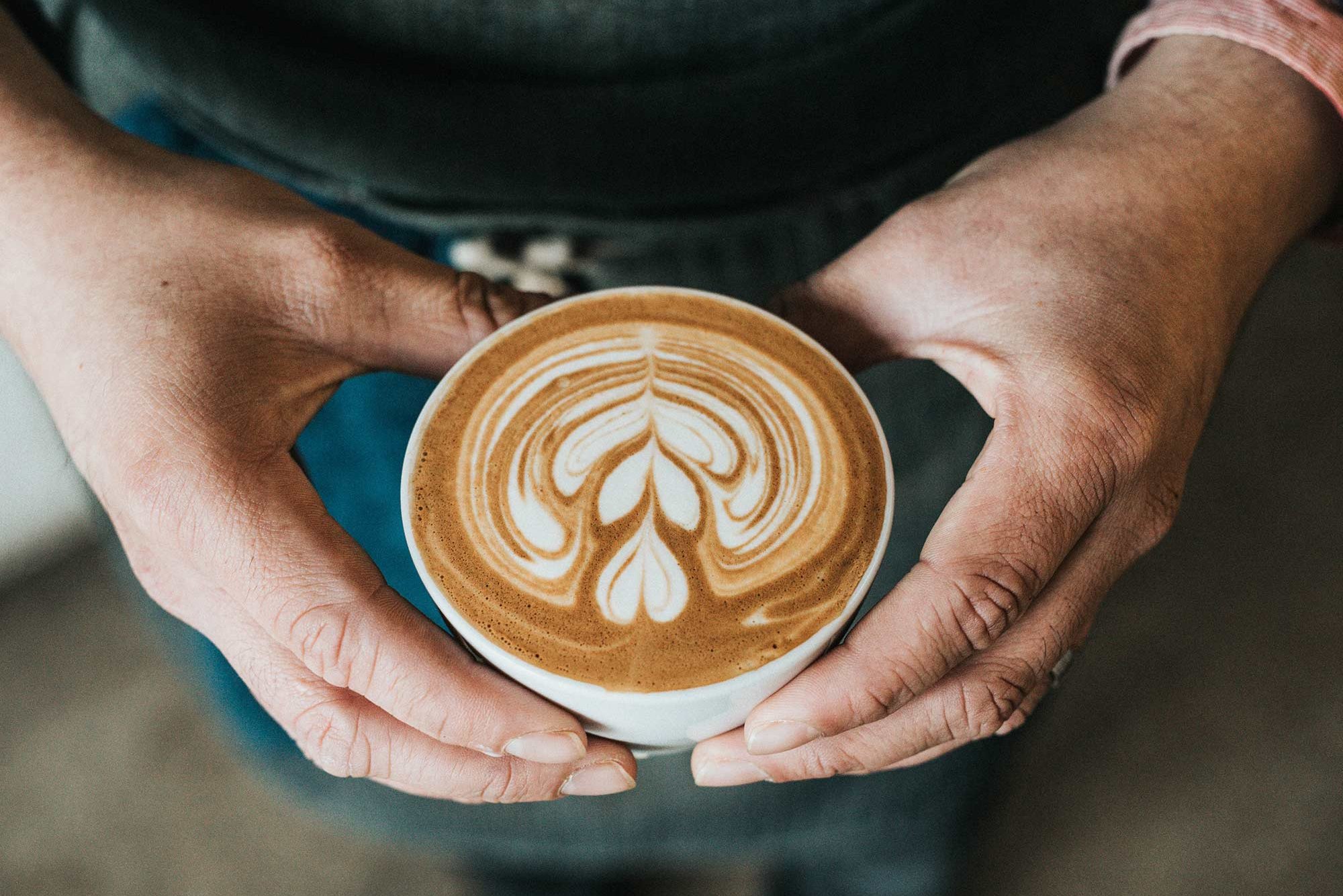 Mann mit einem Cappuccino in der Hand