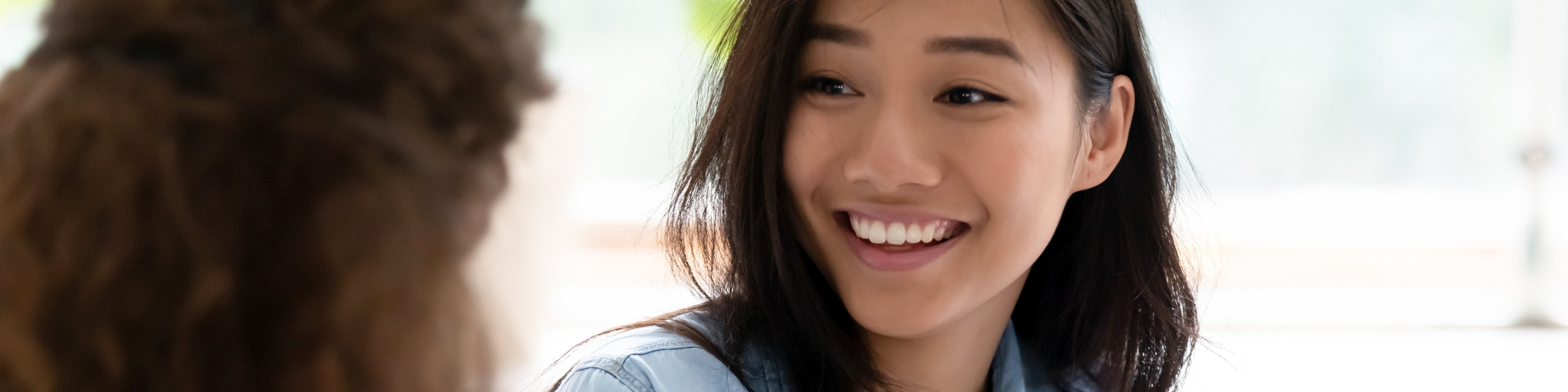 Zwei internationale Studentinnen sitzen nebeneinander und unterhalten sich