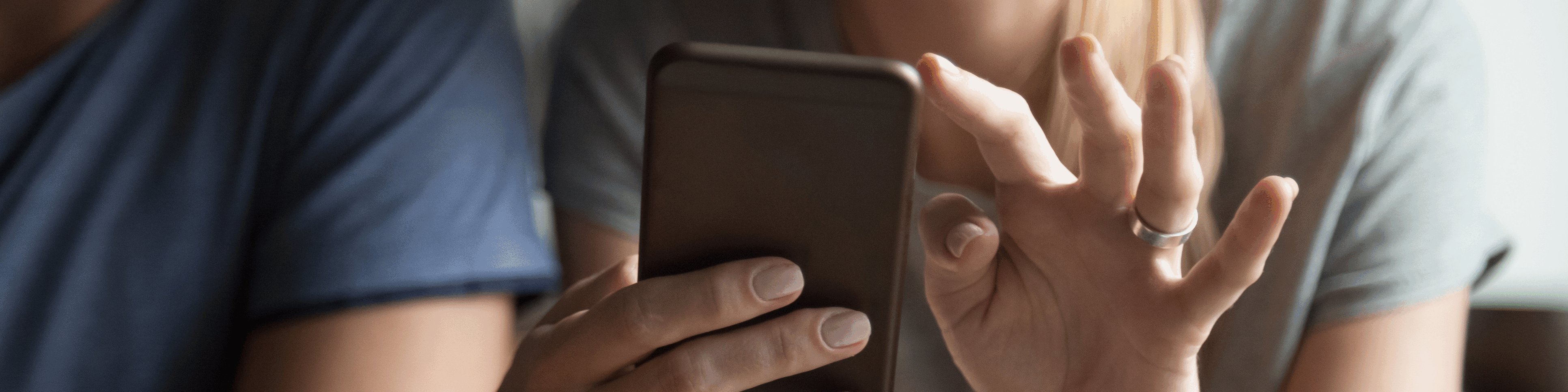 Mann und Frau mit einem Handy in der Hand sitzen an einem Tisch