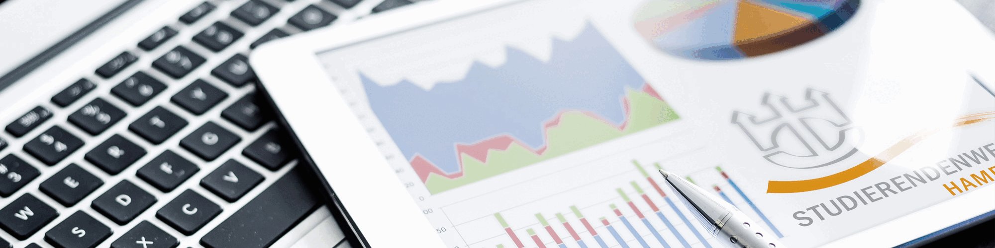 Aufgeklappter Laptop mit Zeitung und Stift 