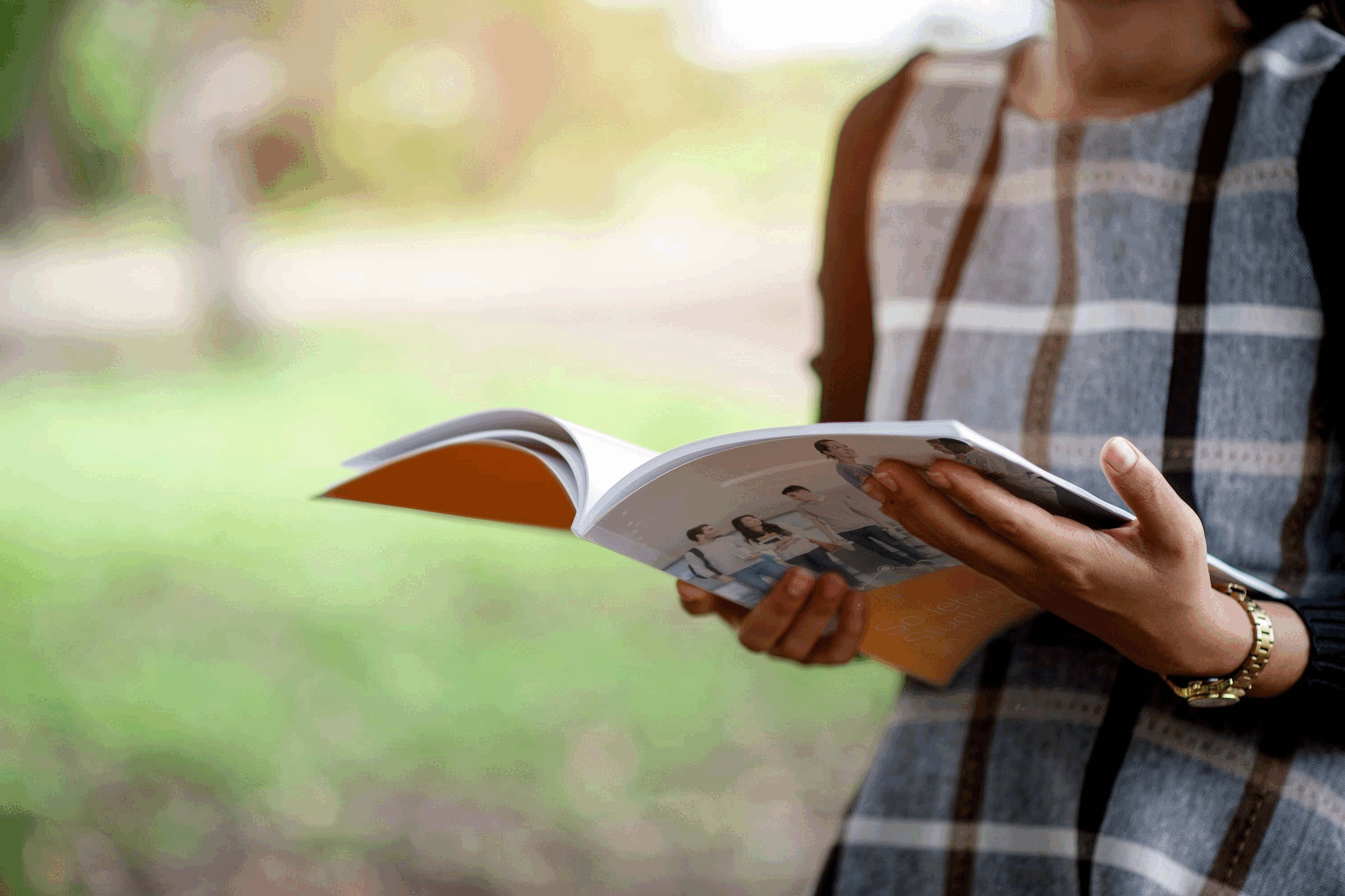 Frau im Park mit einem Magazin in den Händen Frau im Park mit einem Magazin in den Händen