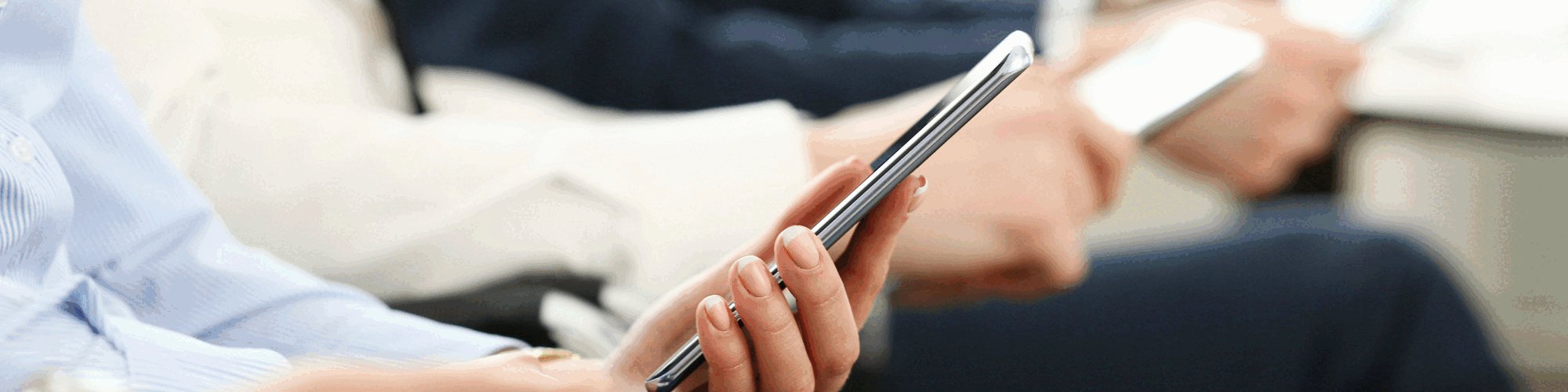 Vier Menschen sitzen mit Smartphone und Tablet nebeneinander