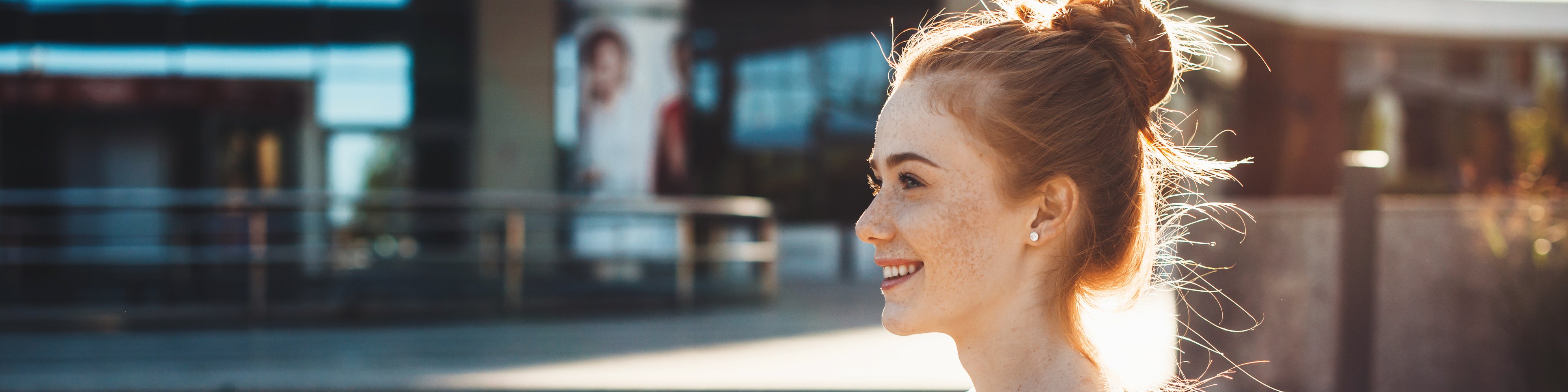 Junge Frau steht vor einem Gebäude und hält Bücher in den Händen